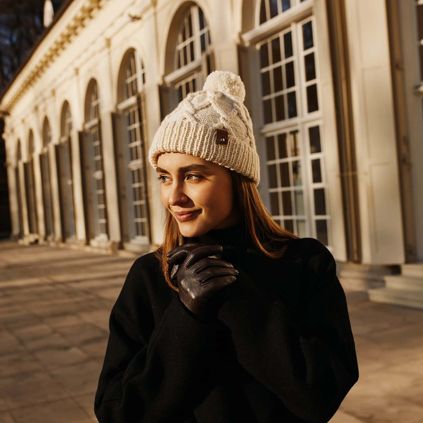 Czapka wełniana z pomponem CLASSIC No 3 ecru Czapka wełniana ręcznie robiona na drutach z pomponem CLASSIC No 3 ecru zestawiona z czarnym płaszczem