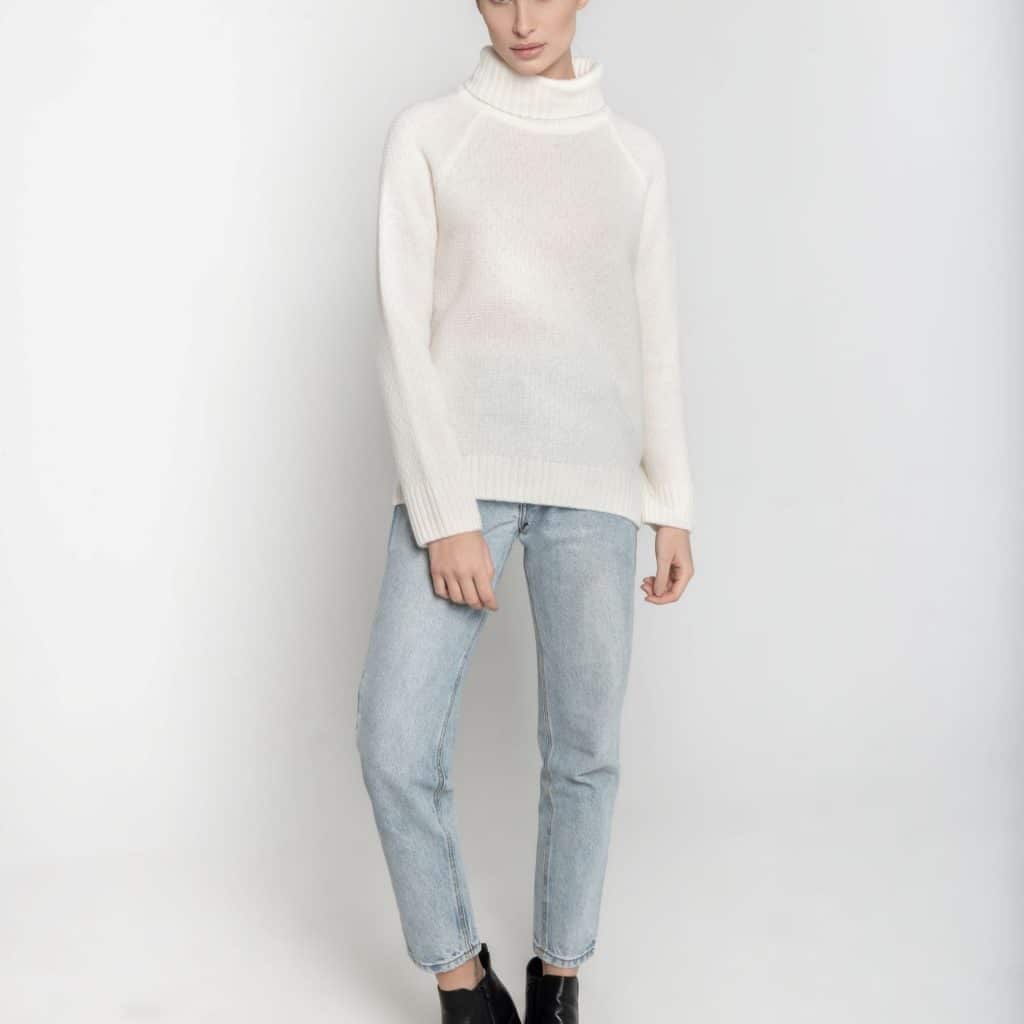 Ręcznie robiony na drutach biały golf z merynosa ESSENTIAL No 1 - widok na modelce z przodu. Zestawiony z jasnymi dżinsami i czarnymi botkami.
