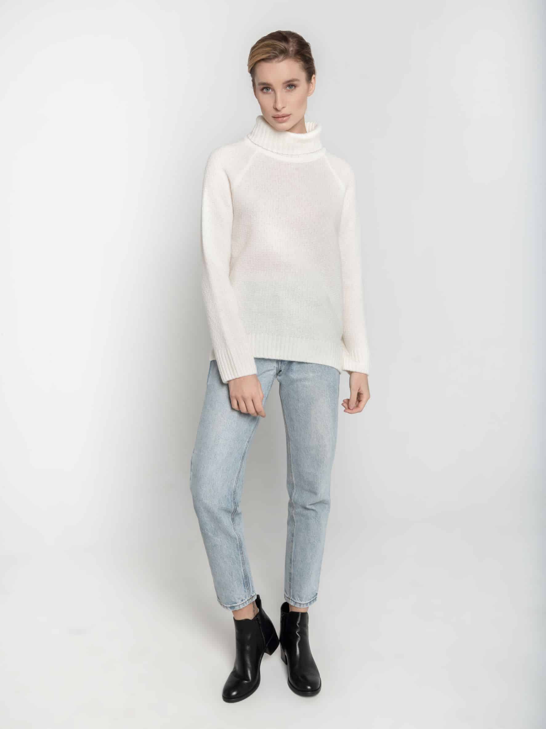 Golf z wełny merynosa - ESSENTIAL No 1 śmietankowa biel Ręcznie robiony na drutach biały golf z merynosa ESSENTIAL No 1 - widok na modelce z przodu. Zestawiony z jasnymi dżinsami i czarnymi botkami.
