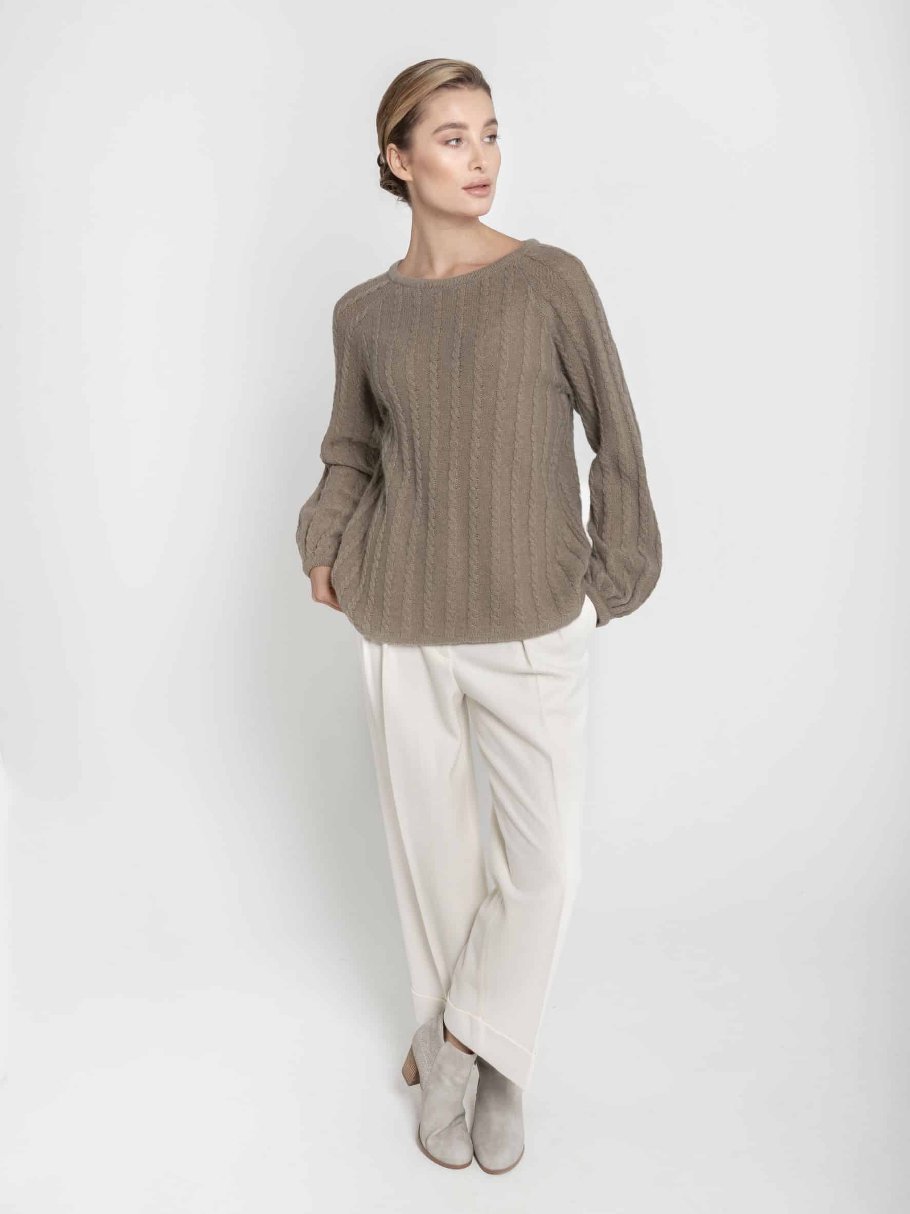 Sweter z wełny merynosa i kaszmiru - ESSENTIAL No 1 taupe Ręcznie robiony na drutach sweter z merynosa i kaszmiru ESSENTIAL No 1 taupe z bufiastymi rękawami - widok z przodu na modelce. Zestawiony z białymi spodniami i szarymi botkami.