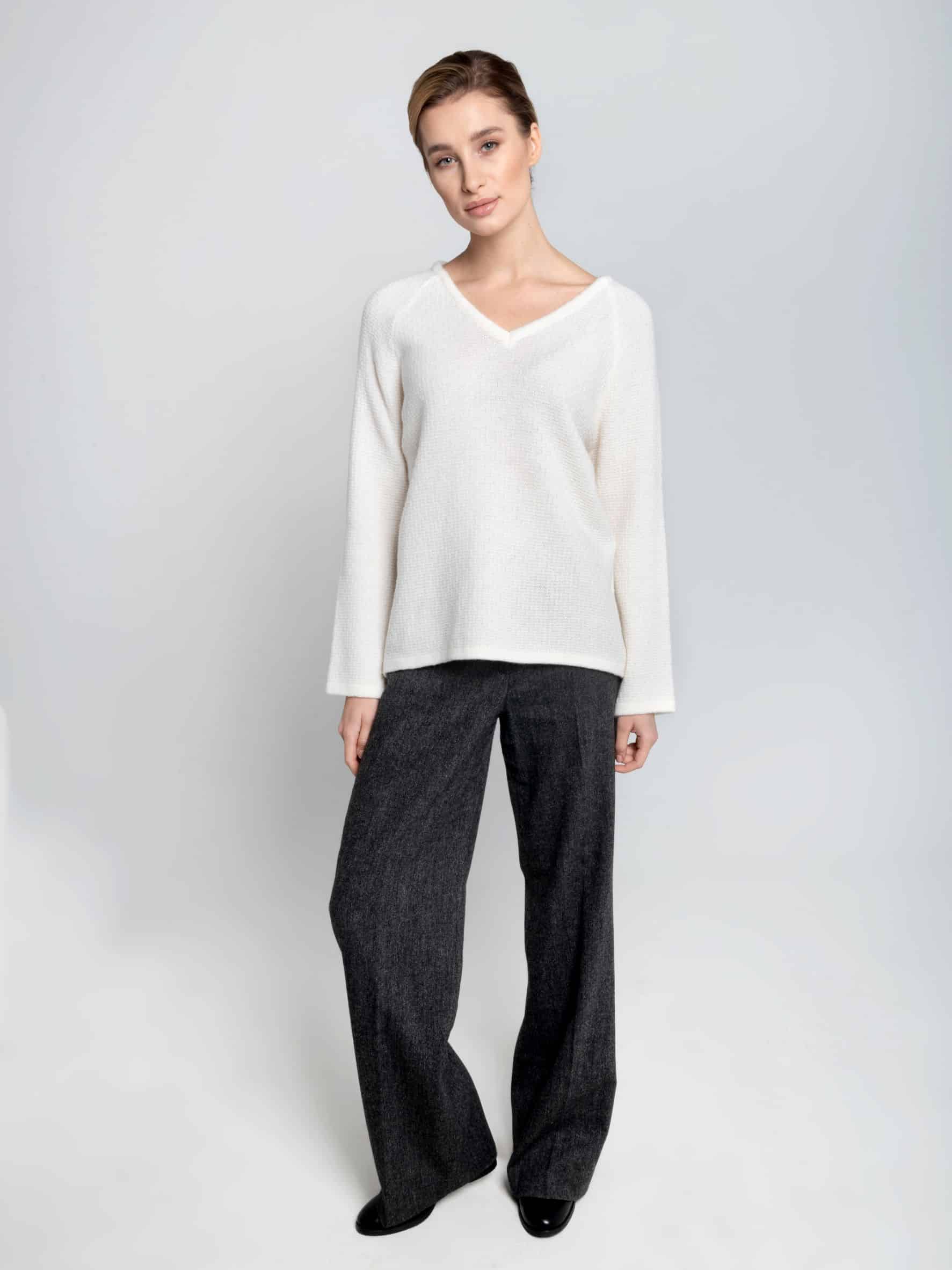 Sweter z merynosa ESSENTIAL V-neck No 1 śmietankowa biel Biały sweter z merynosa z dekoltem w serek ESSENTIAL V-neck No 1 na modelce zestawiony z ciemnoszarymi spodniami