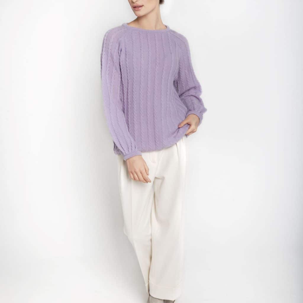 Liliowy sweter z merynosa i kaszmiru ESSENTIAL No 1 z warkoczowym splotem i bufiastymi rękawami zestawiony z białymi spodniami i szarymi botkami