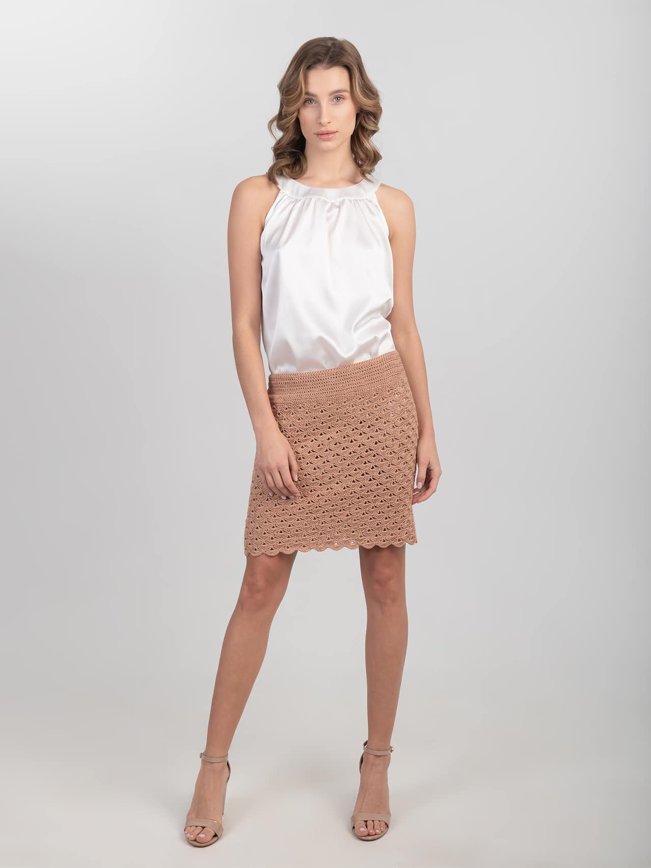Jedwabna bluzka bez rękawów biała Biała jedwabna bluzka bez rękawów zestawiona z beżową spódnicą i beżowymi sandałami - widok na modelce z przodu