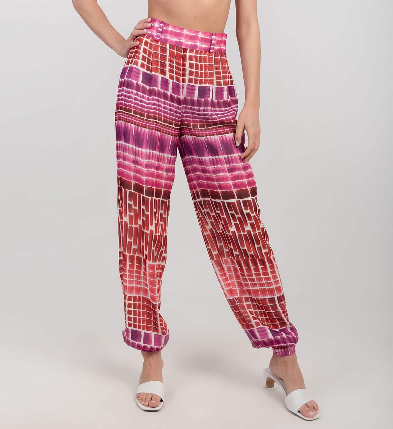 Jedwabne wzorzyste spodnie - LIMITED EDITION Wzorzyste spodnie z jedwabiu w odcieniach czerwieni i różu z wysokim stanem i bufiastymi nogawkami zestawione z białymi klapkami na obcasie