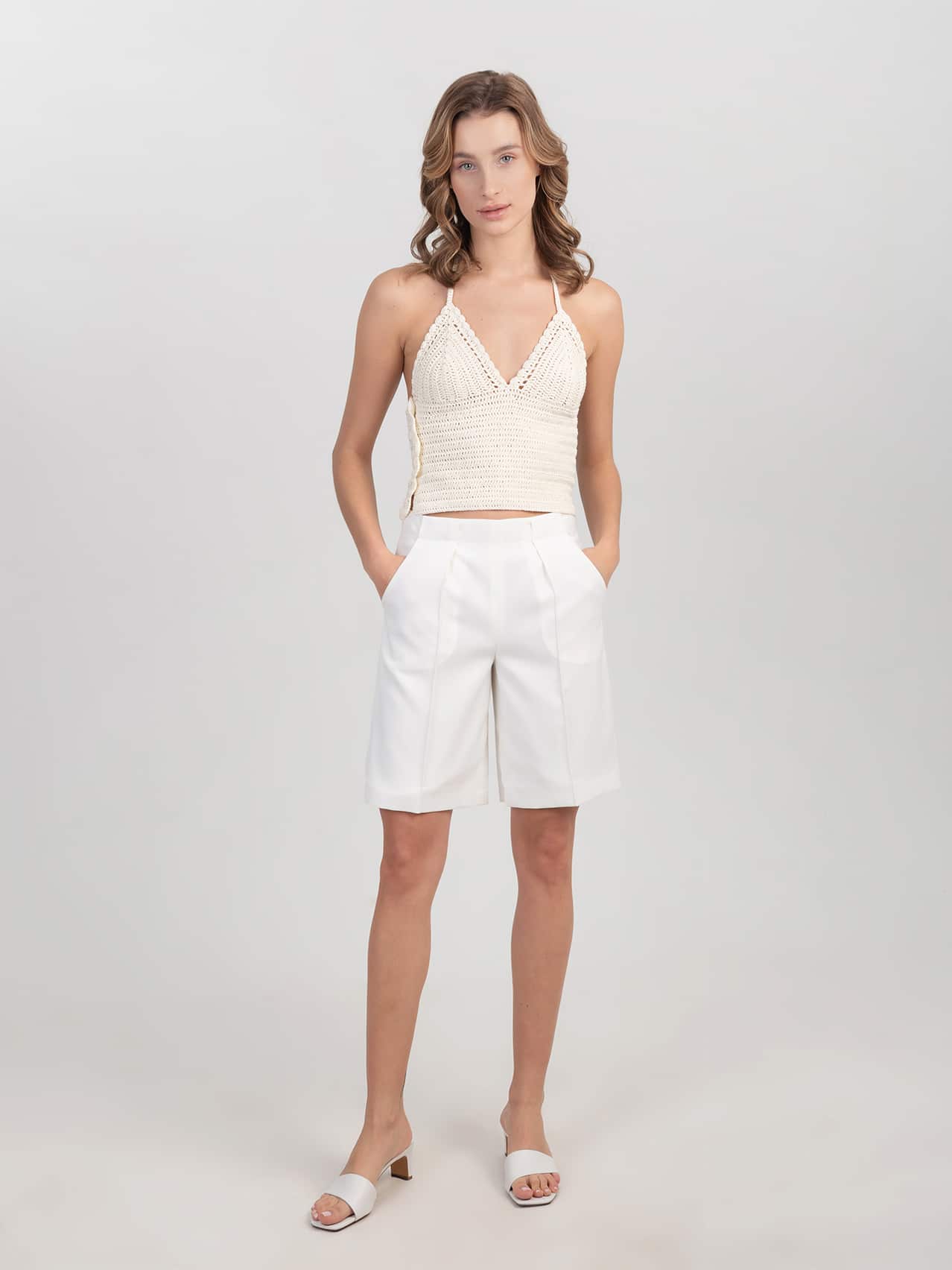 Wełniane szorty w śmietankowej bieli Białe wełniane szorty zestawione z szydełkowym topem i klapkami na obcasie