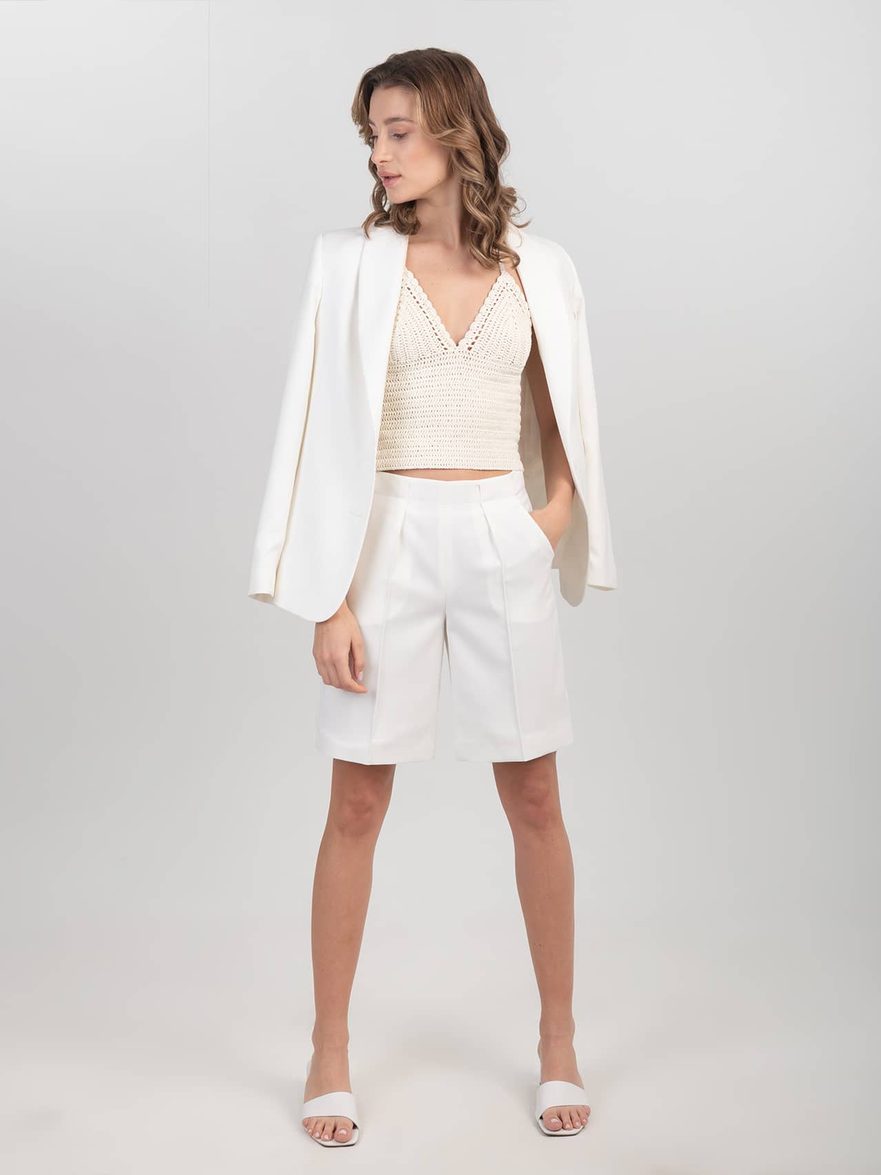 Wełniane szorty w śmietankowej bieli Wełniane białe szorty zestawione z szydełkowym topem, wełnianą marynarką i klapkami na obcasie