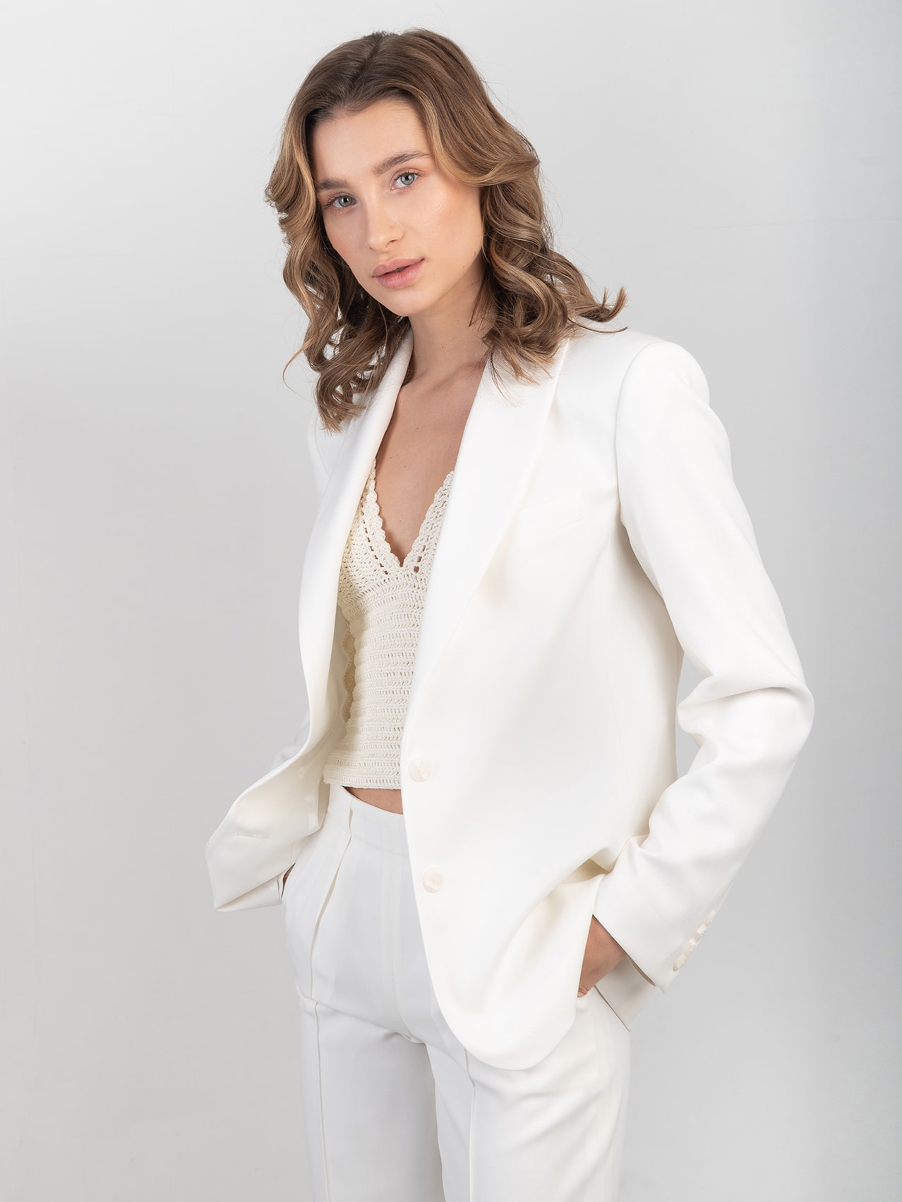 Wełniana smokingowa marynarka w śmietankowej bieli Damska biała wełniana marynarka zestawiona ze spodniami z kompletu i szydełkowym topem