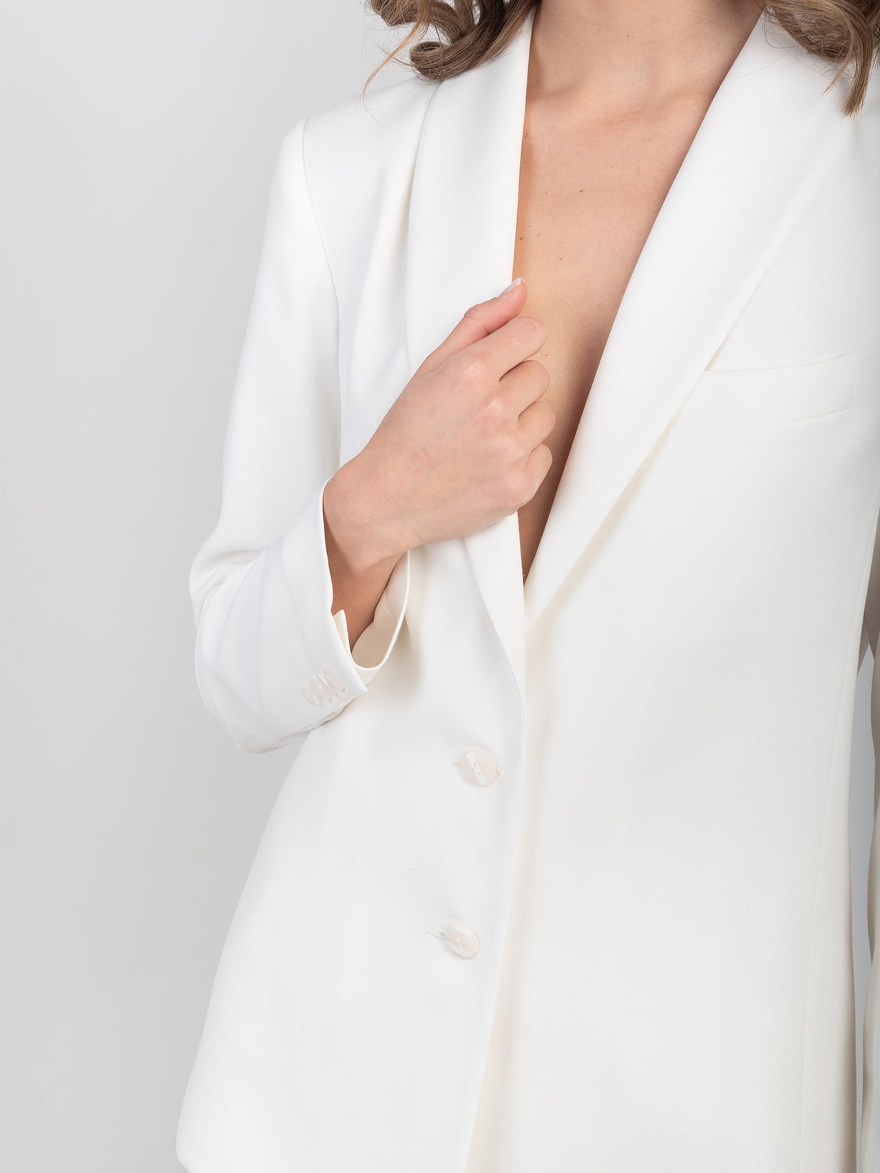 Wełniana smokingowa marynarka w śmietankowej bieli Biała wełniana marynarka smokingowa - zbliżenie na wykończenie dekoltu